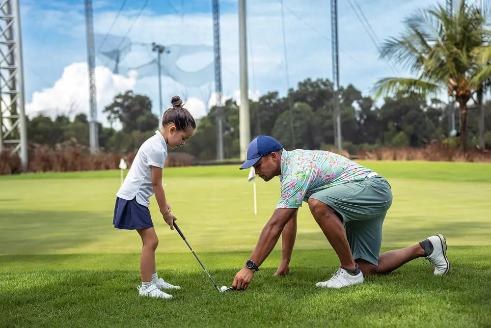 Child learning golf from an adult